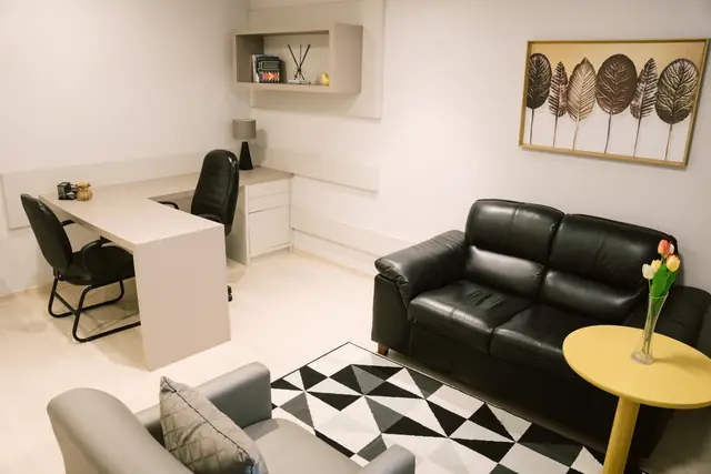 Sala 101 da Willtay em Brusque: mesa de trabalho em L, área de estar com sofá de couro e poltrona
