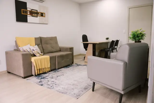 Sala 108 da Willtay em Brusque: sofá de três lugares, poltrona e mesa de trabalho ao fundo