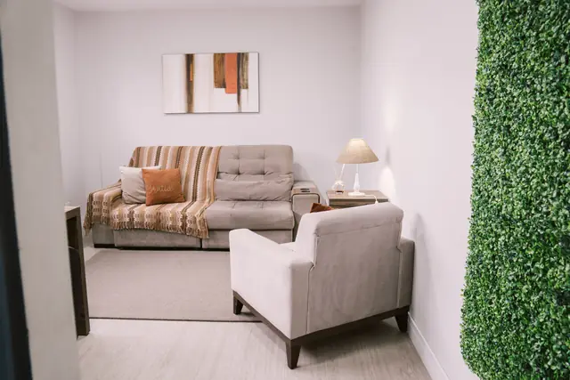 Sala 213 da Willtay em Brusque: sofá, poltrona, luminária e parede verde, com mesa de trabalho